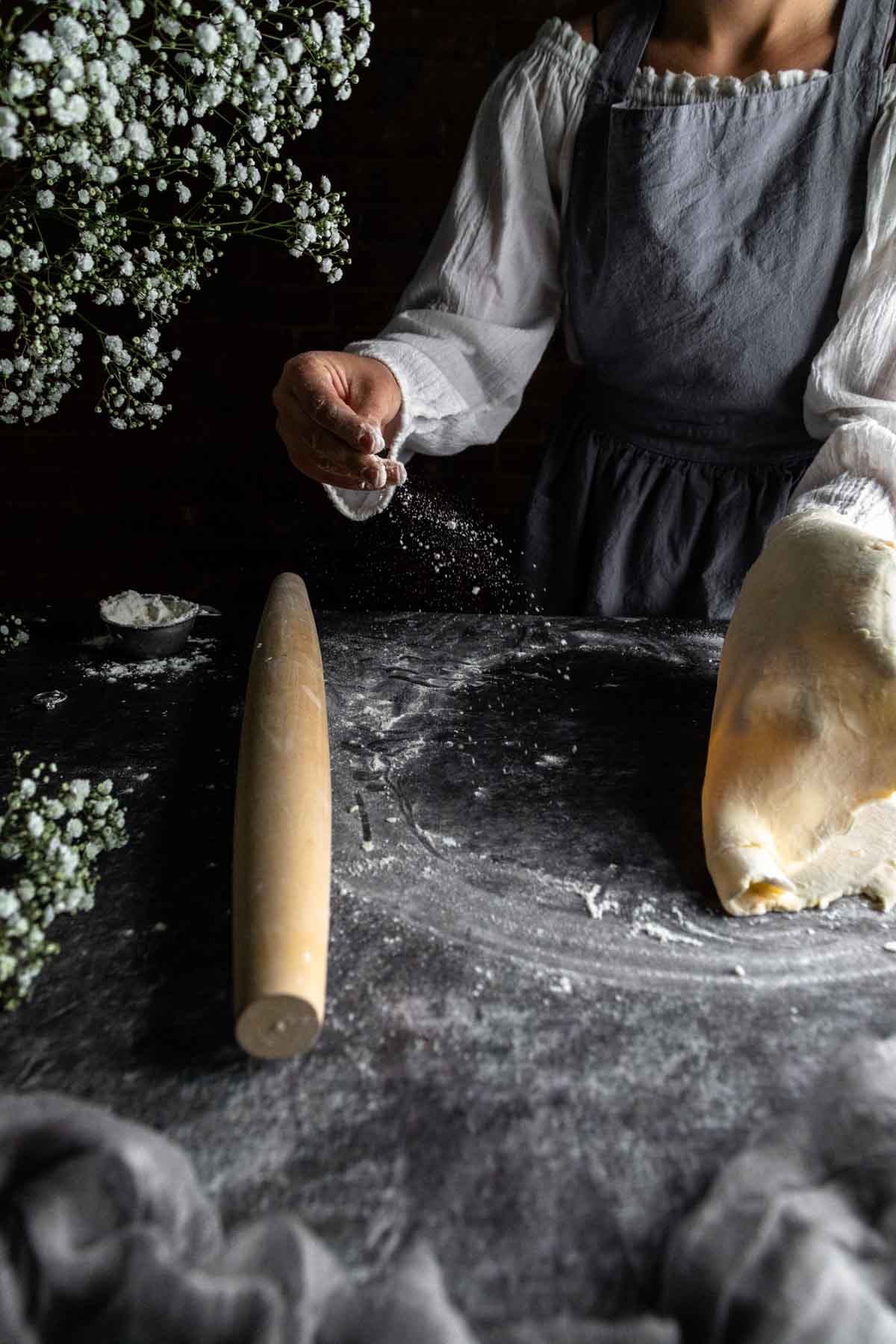 A woman sprinkling flour onto pie dough