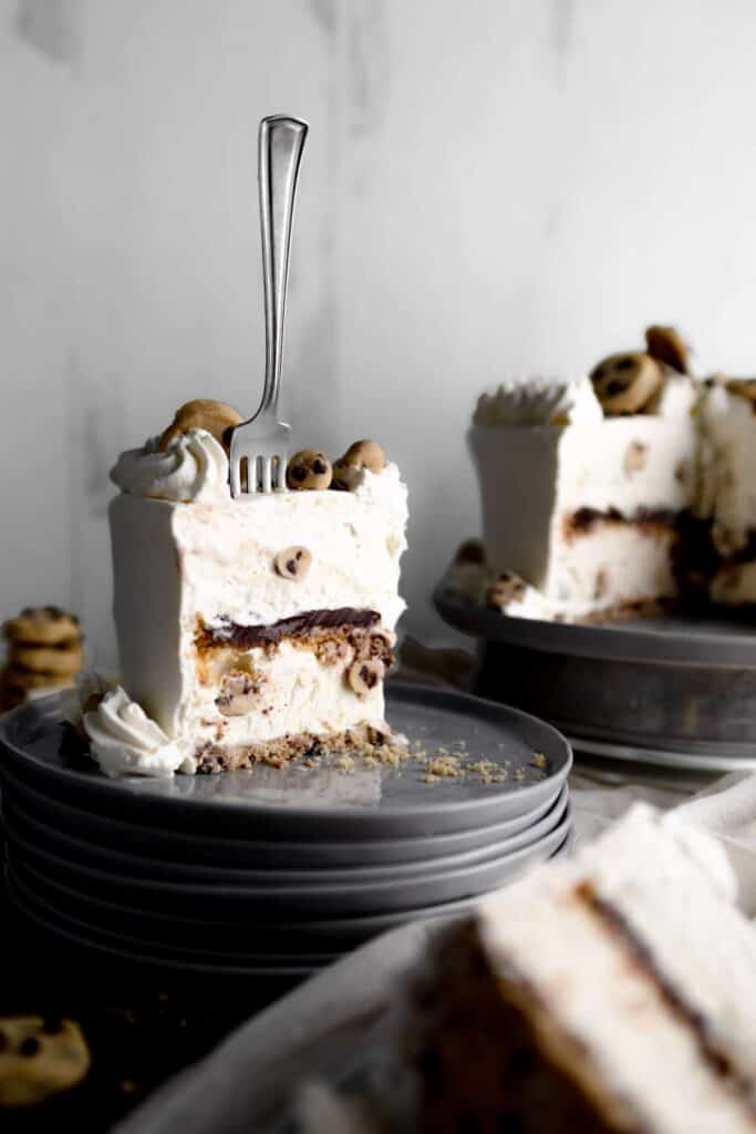 A fork standing in a slice of Cookie Dough Ice Cream Cake