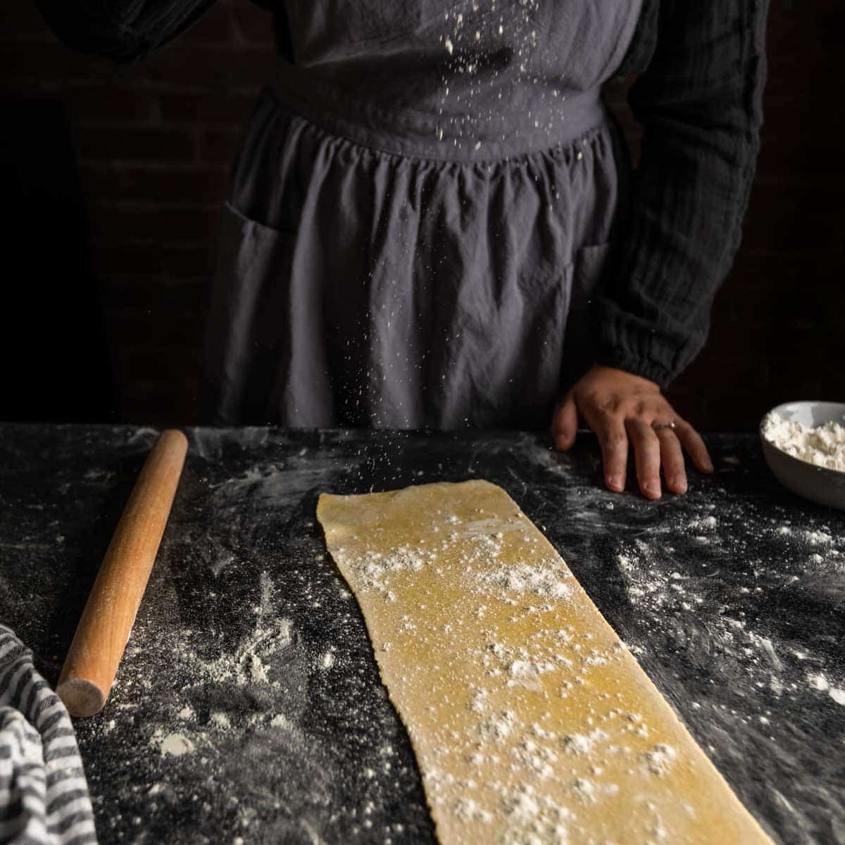 dusting a sprinkle of flour over a sheet of pasta dough