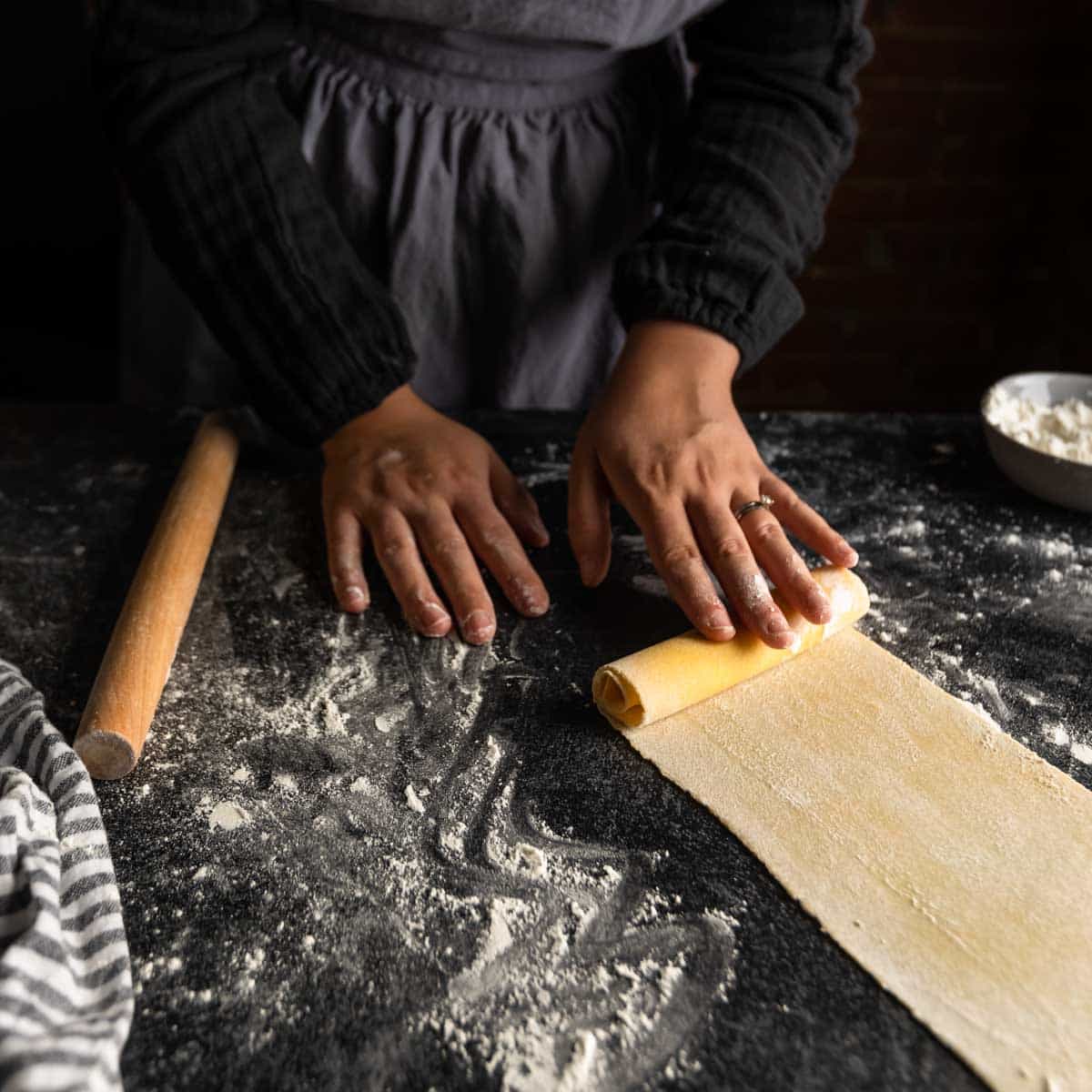 rolling a long sheet of pasta dough into a log