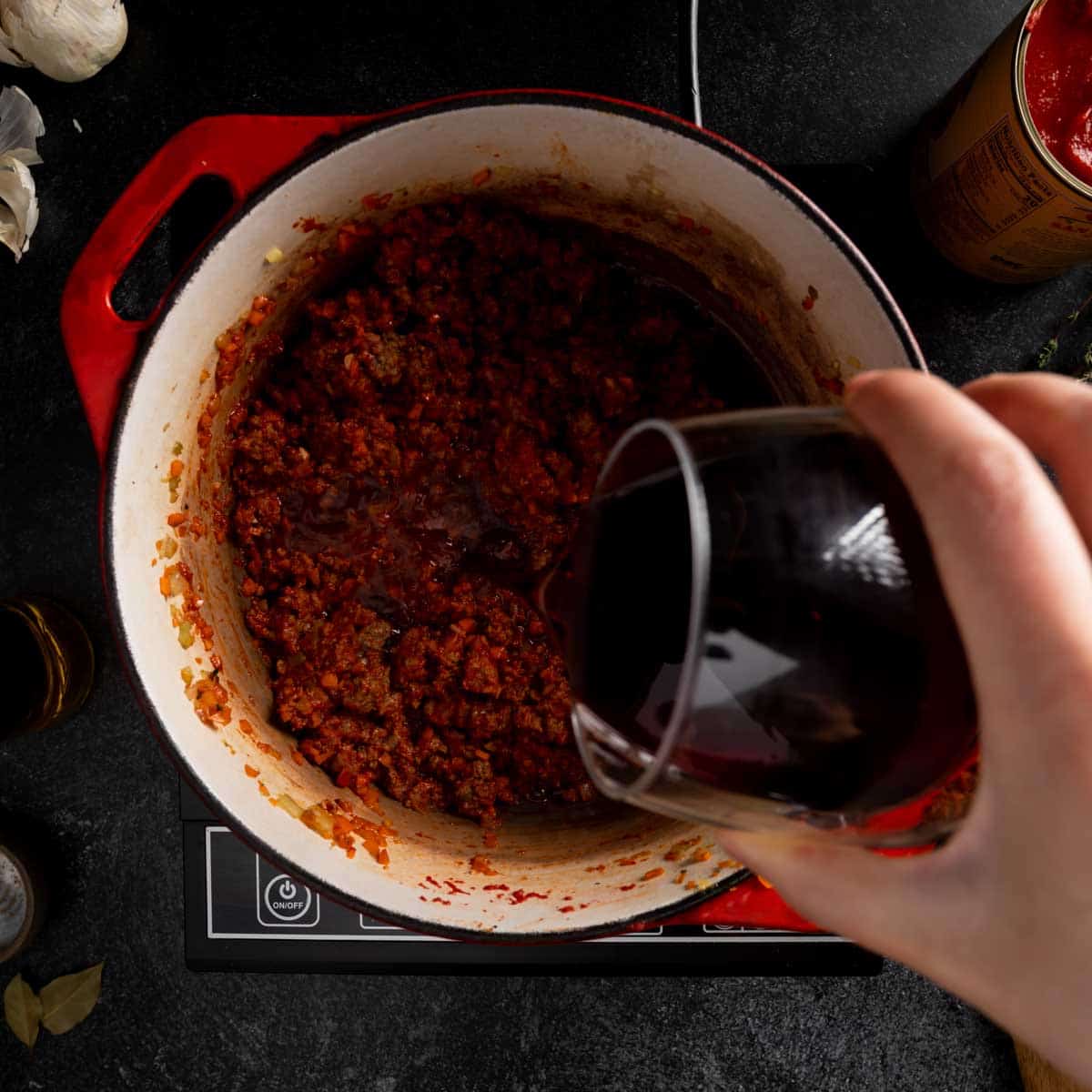 Pouring red wine into the Bolognese sauce