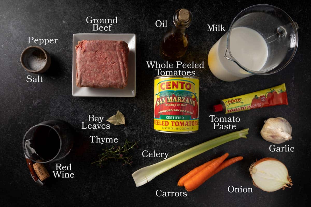 Ingredients needed for ragu alla Bolognese including olive oil, onion, carrot, celery, garlic, tomato paste, San Marzano tomatoes, ground beef, red wine, milk, salt, pepper, bay leaves and fresh thyme. 