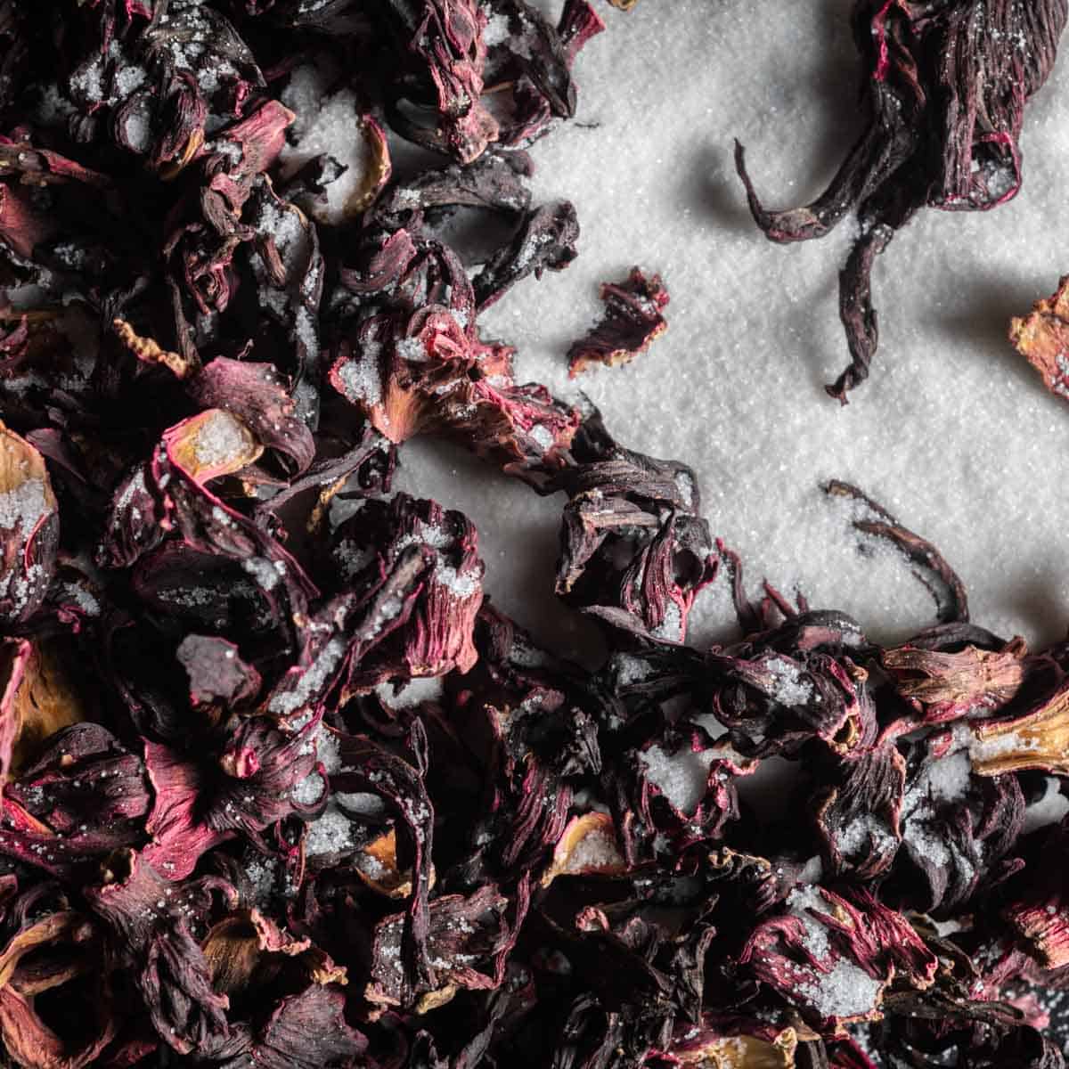 a close up shot of dried hibiscus flowers and granulated sugar