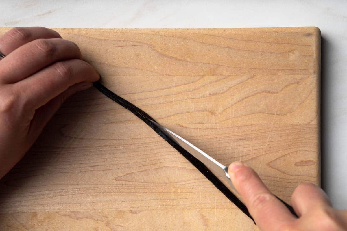 Using a paring knife to cut a vanilla bean lengthwise