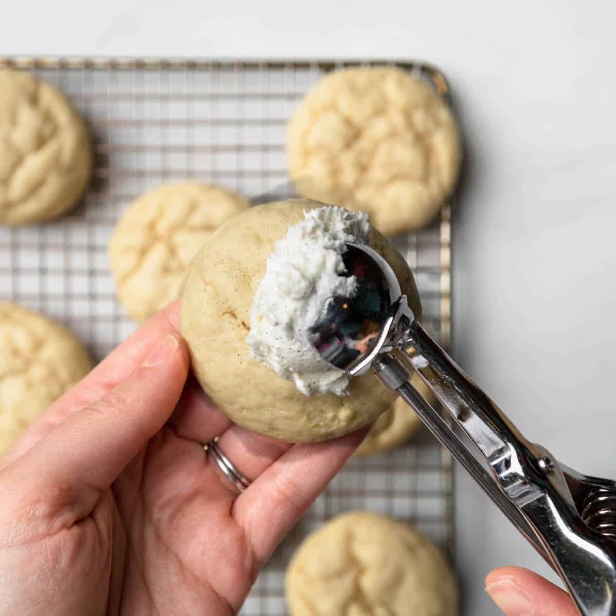Adding a scoop of vanilla frosting to a cookie