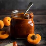 A jar or homemade apricot bbq sauce with a spoon in it