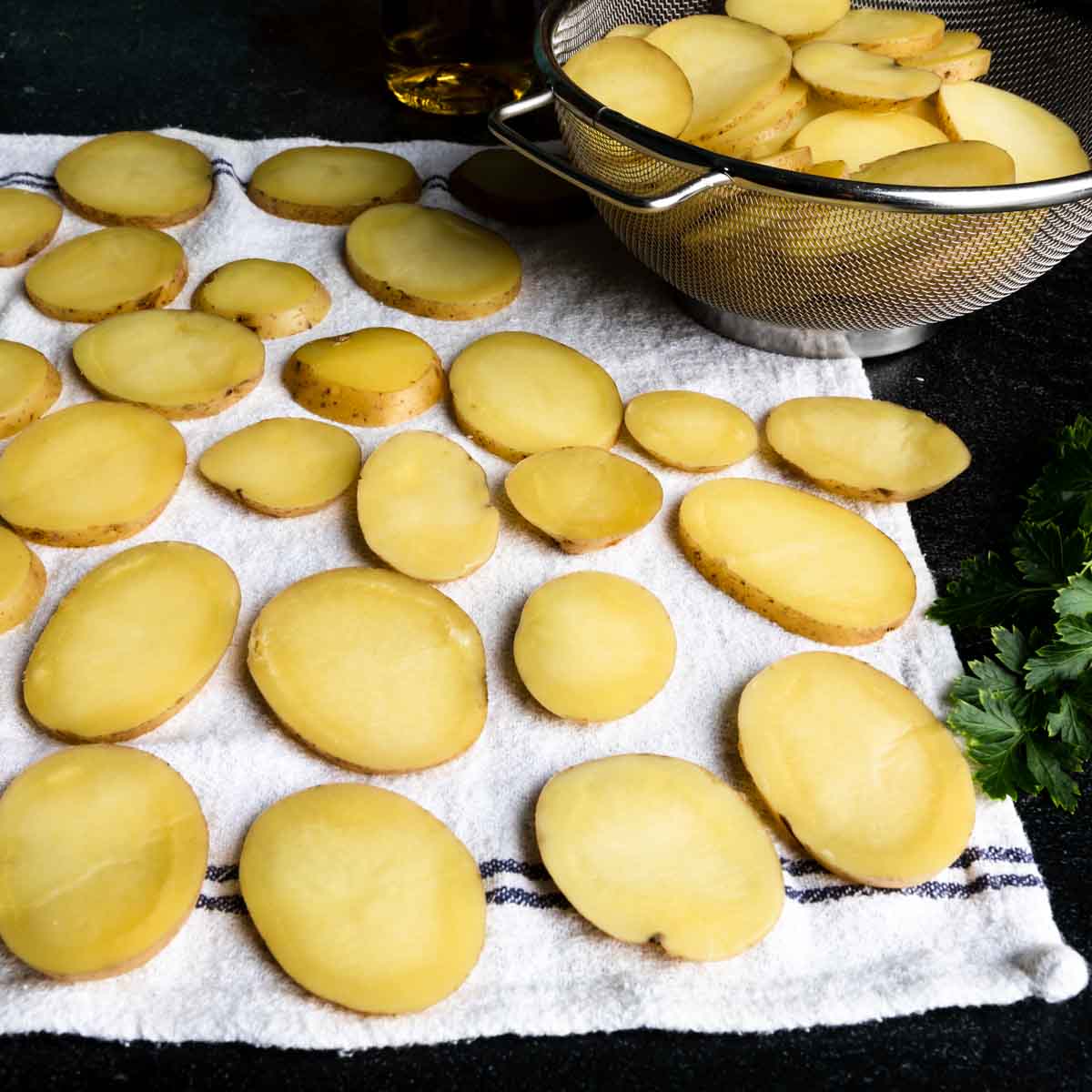 Sliced, par-boiled potatoes drying on a clean kitchen towel