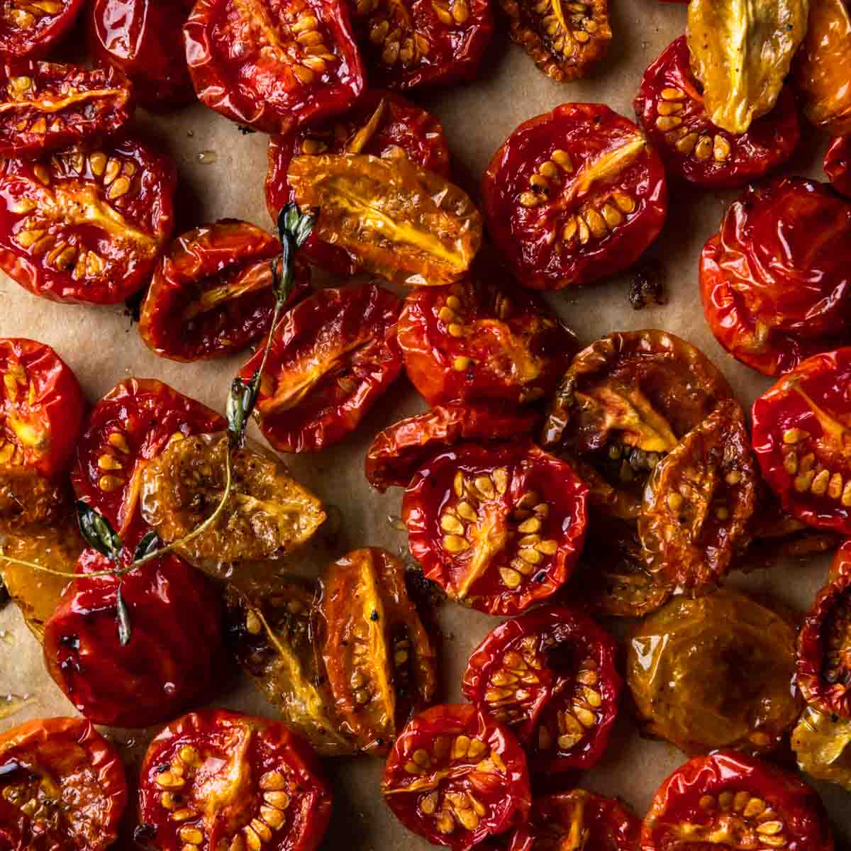 A close up image of oven roasted cherry tomatoes on a sheet pan