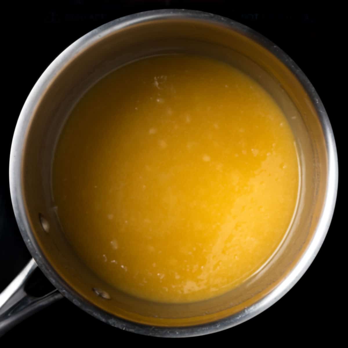 A pot with a smooth mixture of melted butter, sugar and honey