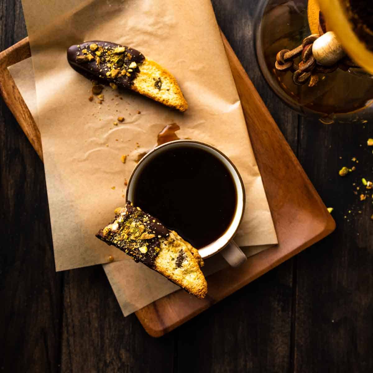 An overhead photo od chocolate dipped biscotti resting on a cup of coffee