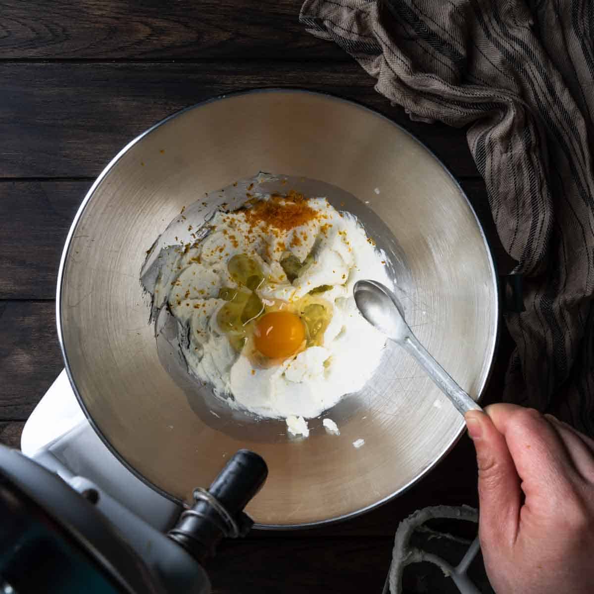 Creamed butter and sugar in a bowl with an egg, orange zest and extract