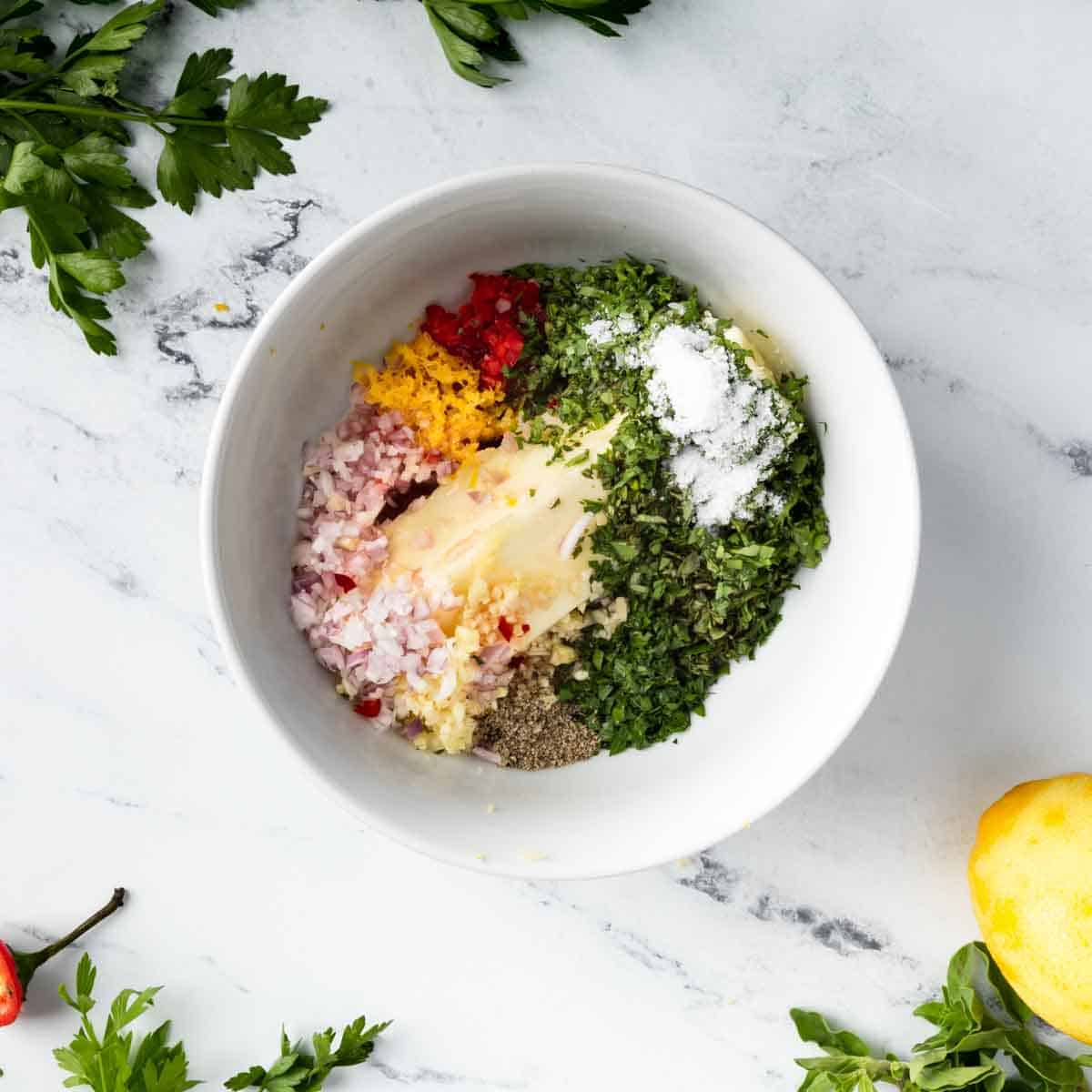 Butter and finely minced chimichurri ingredients in a bowl