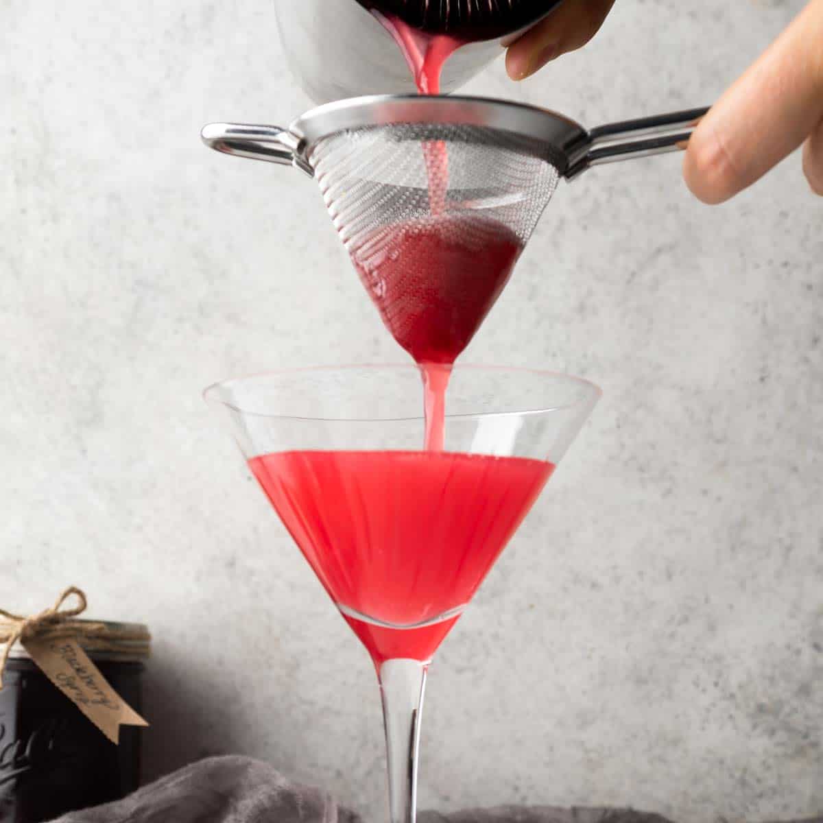 Double straining a cocktail into a martini glass