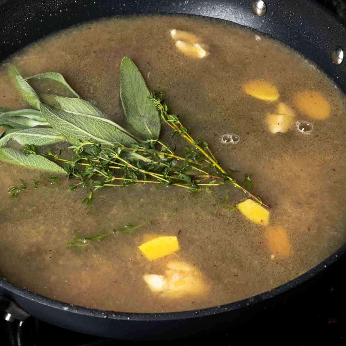 Bringing the cider braising liquid and aromatics to a simmer