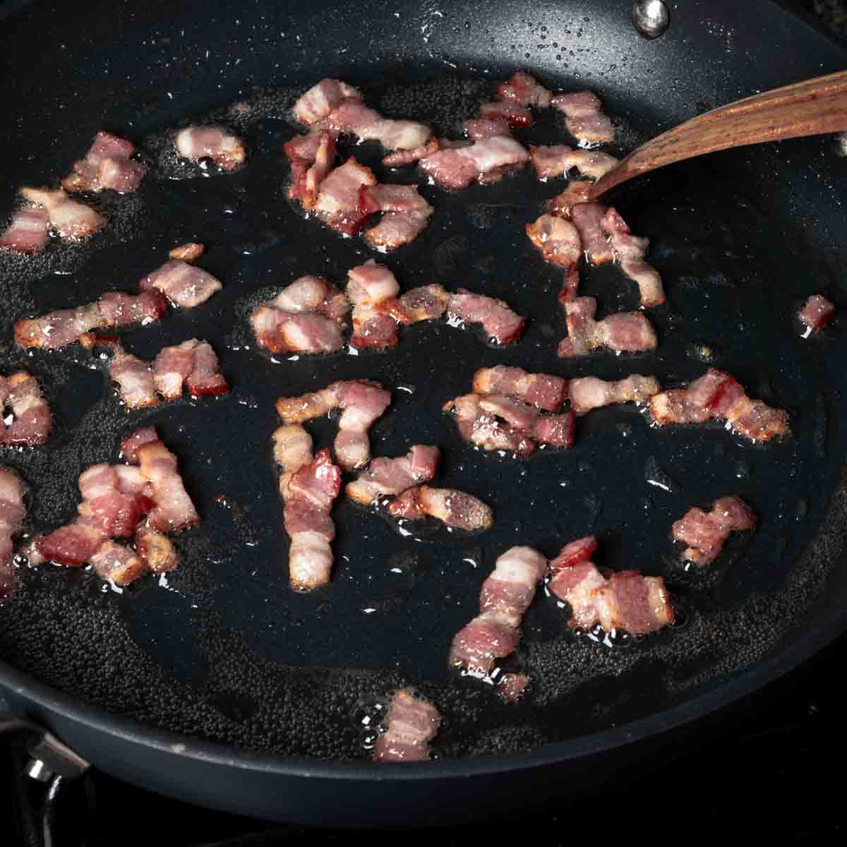 Sautéing chopped bacon in a pan.