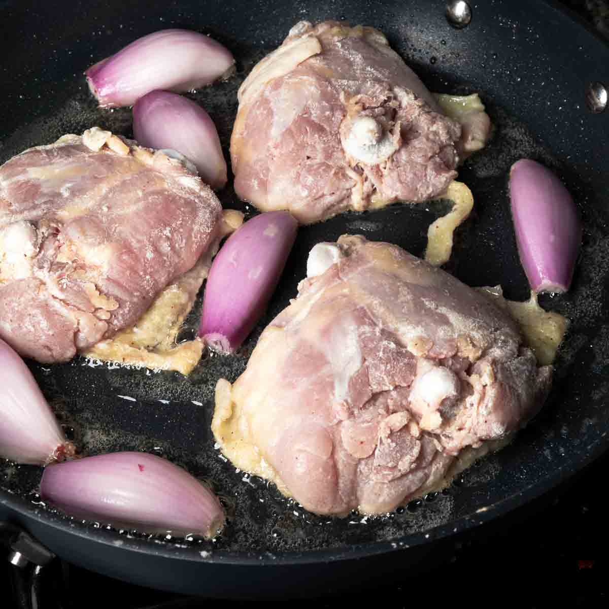 Searing chicken thighs and shallots in bacon fat