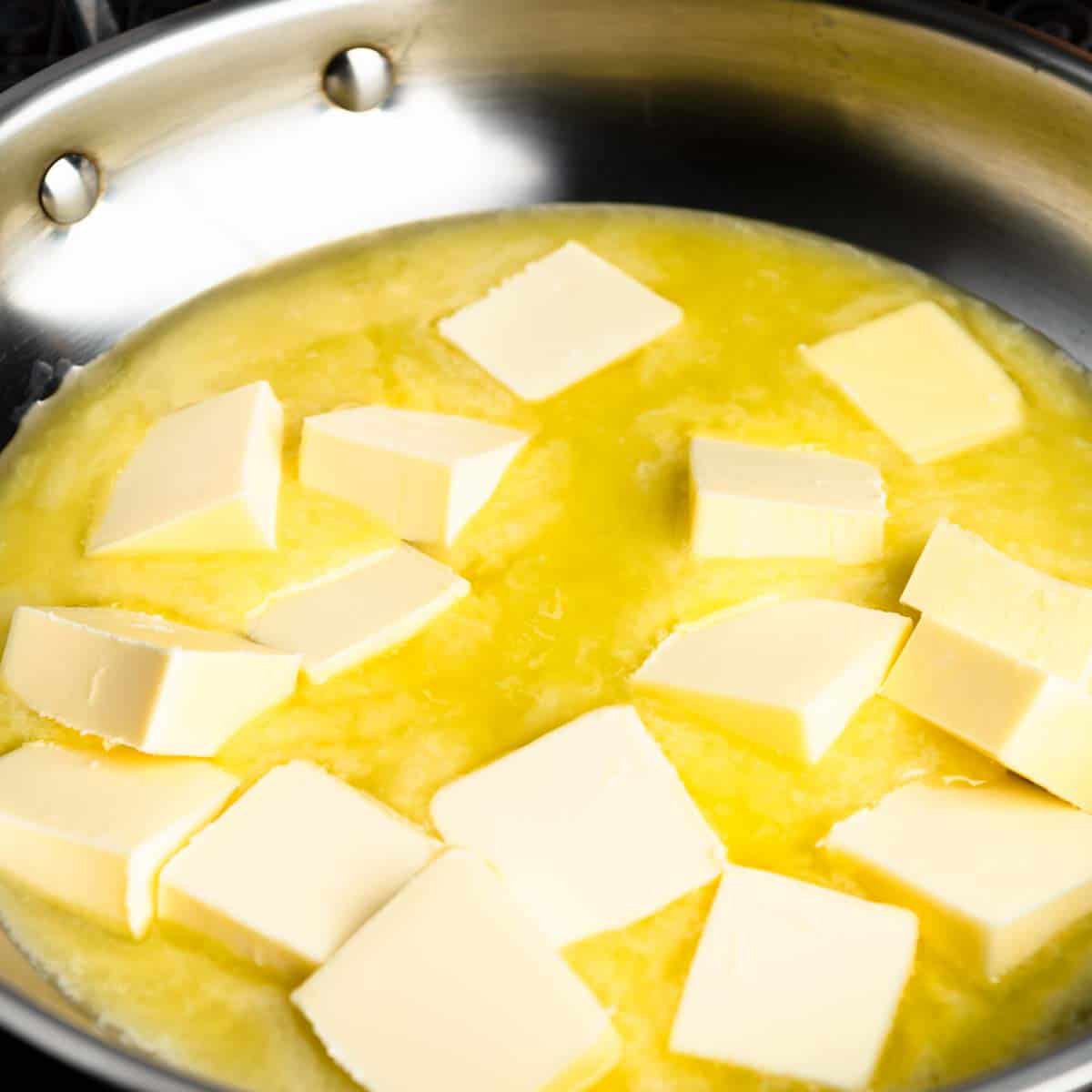 Tablespoons of butter melting in a stainless steel pan