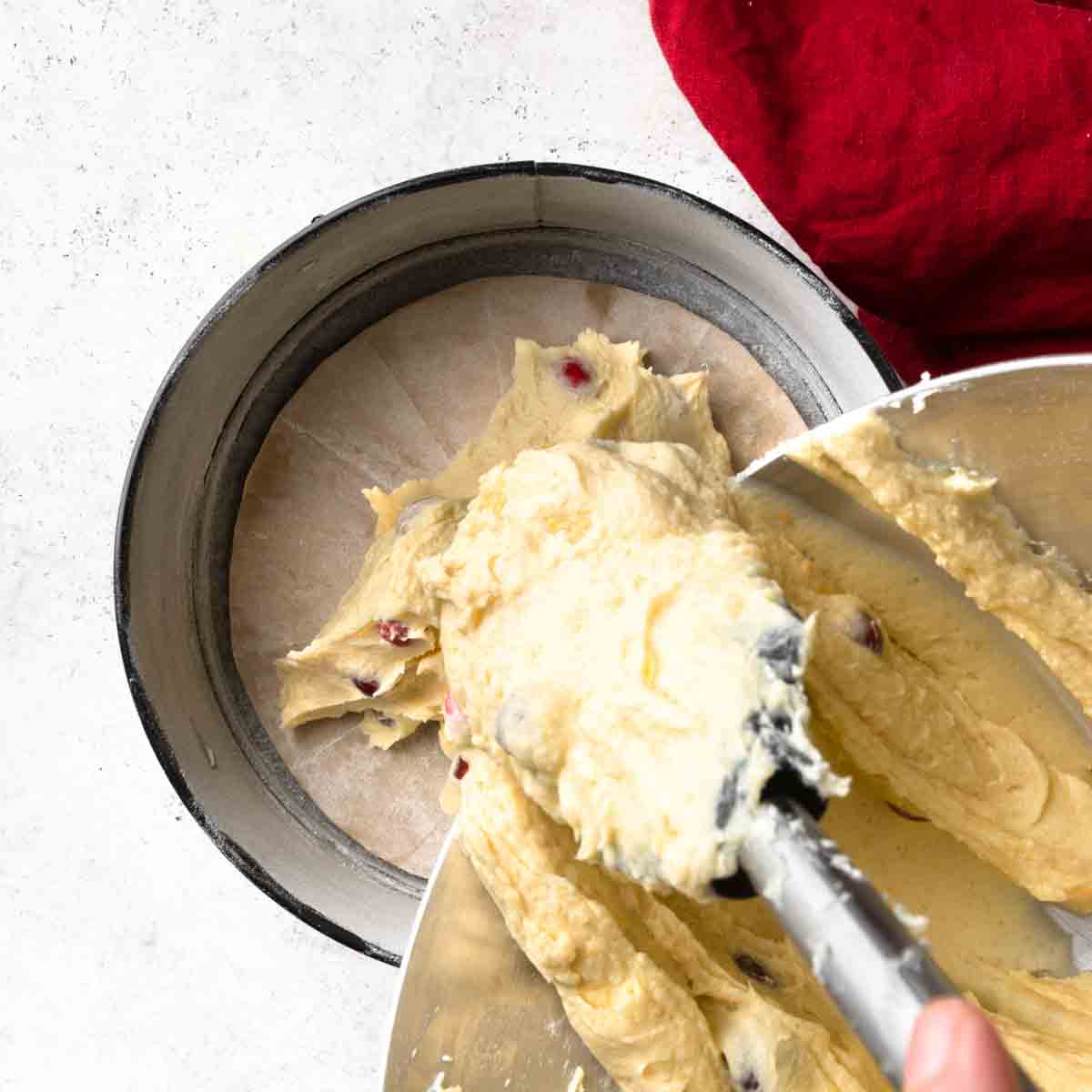 Pouring cake batter into a prepared round cake pan. 