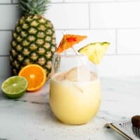 A tropical coconut and pineapple mocktail garnished with fresh pineapple and a cocktail umbrella.