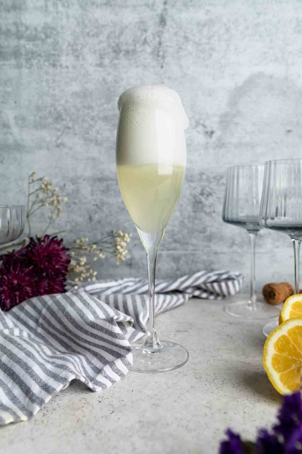 A freshly poured French 76 bubbling over the top of the glass.