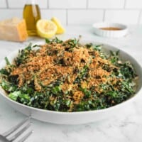A big bowl of Tuscan Kale salad in tahini Parmesan dressing with lots of breadcrumbs.