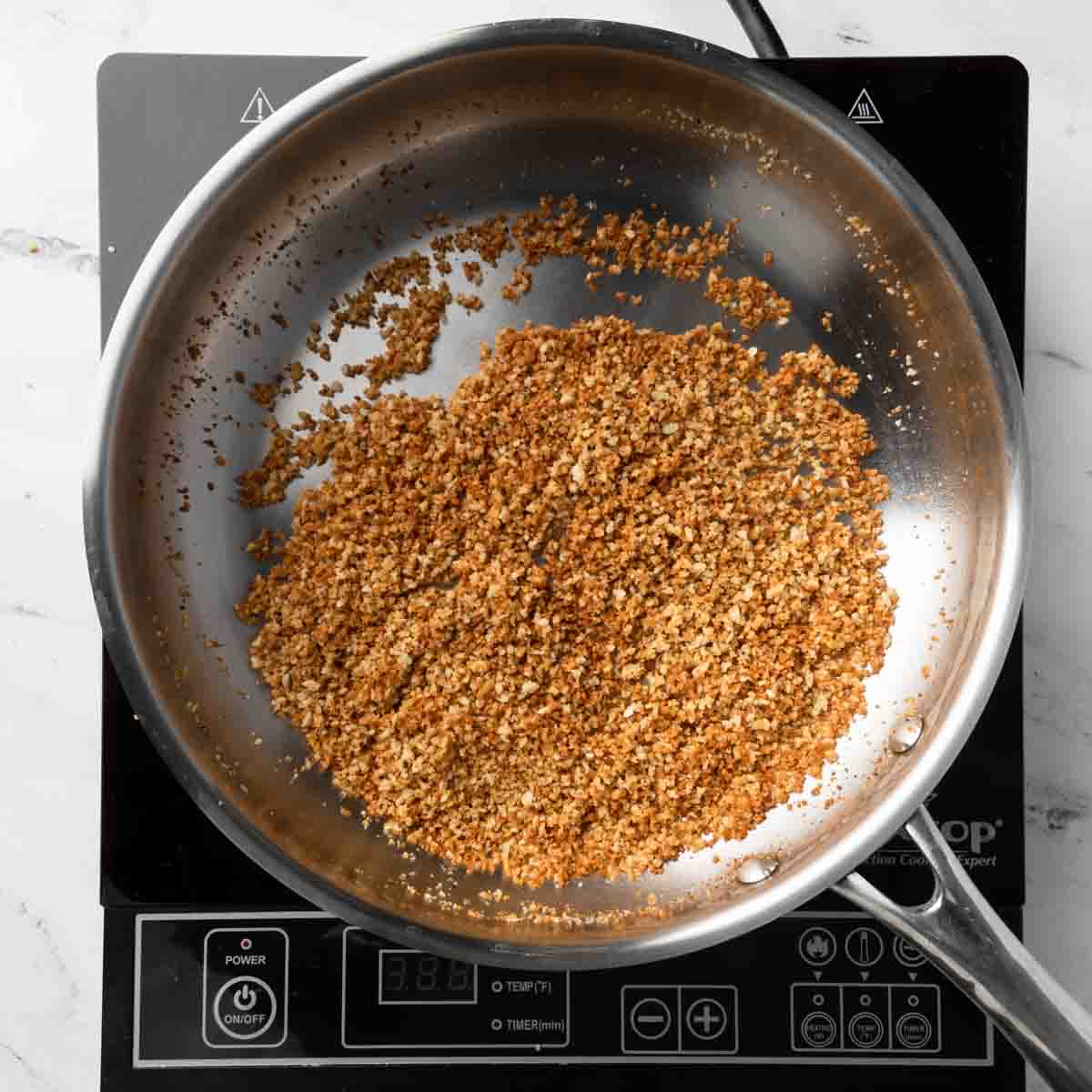 A frying pan with toasted breadcrumbs.
