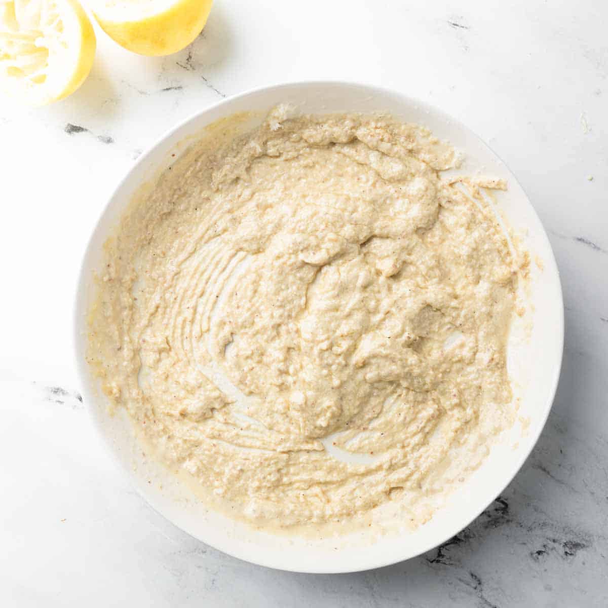 Creamy tahini Parmesan dressing whisked together in a bowl.