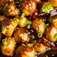 Asian chicken meatballs in a tangy General Tso sauce garnished with scallion and sesame seeds.
