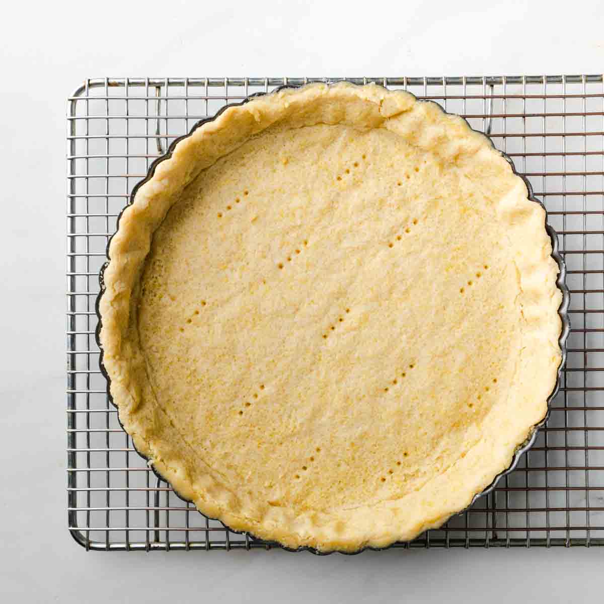 The blind baked pie crust on a cooling rack.