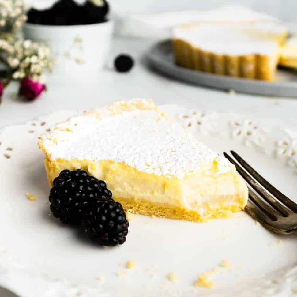 A slice of ricotta pie on a plate missing a bite.